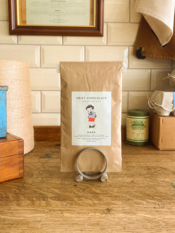 Bar of Heist Dark Chocolate on a wooden surface with a tiled background.