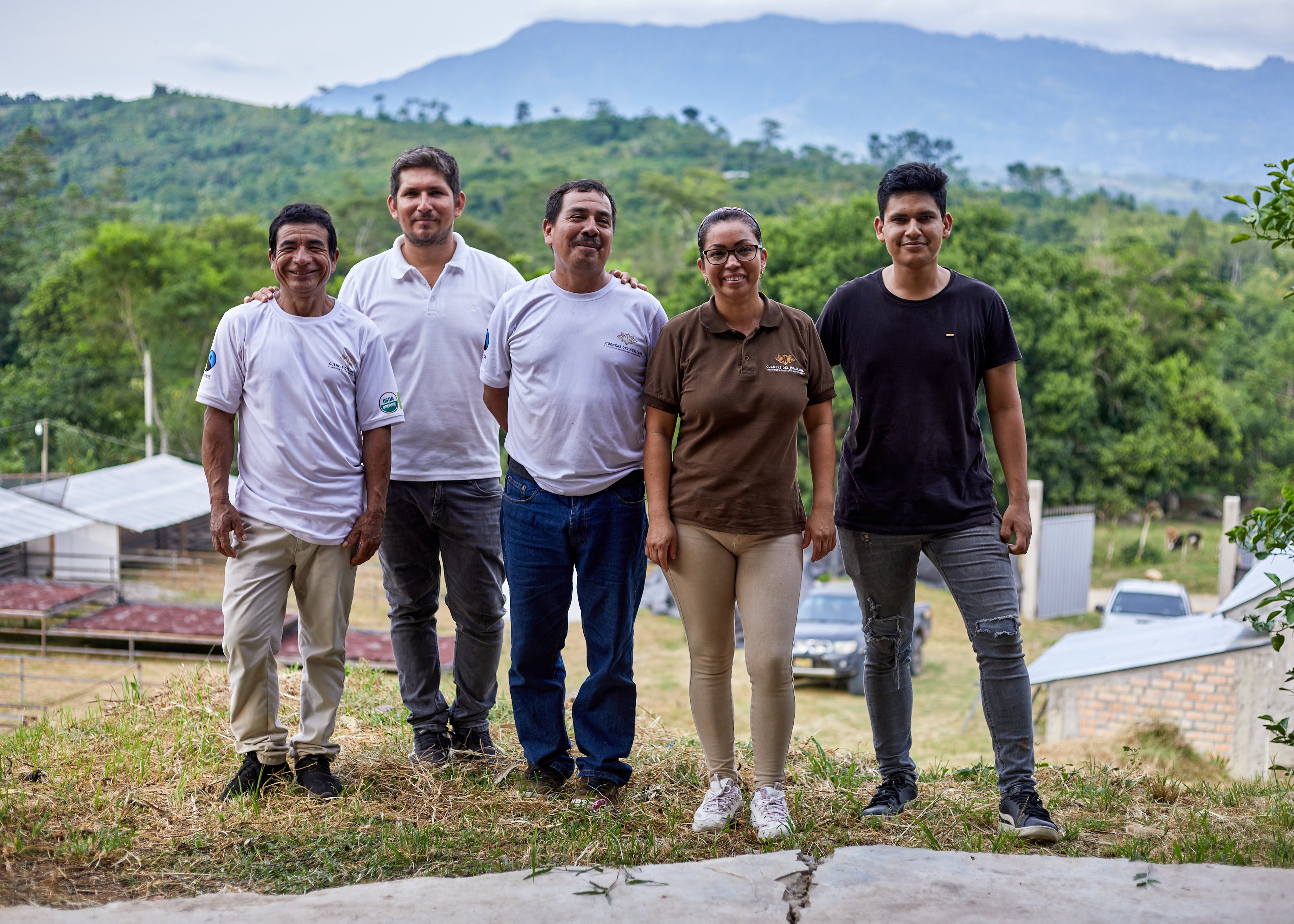 Cuencas Del Huallaga Coop Employees, smiling in front of drying cacao