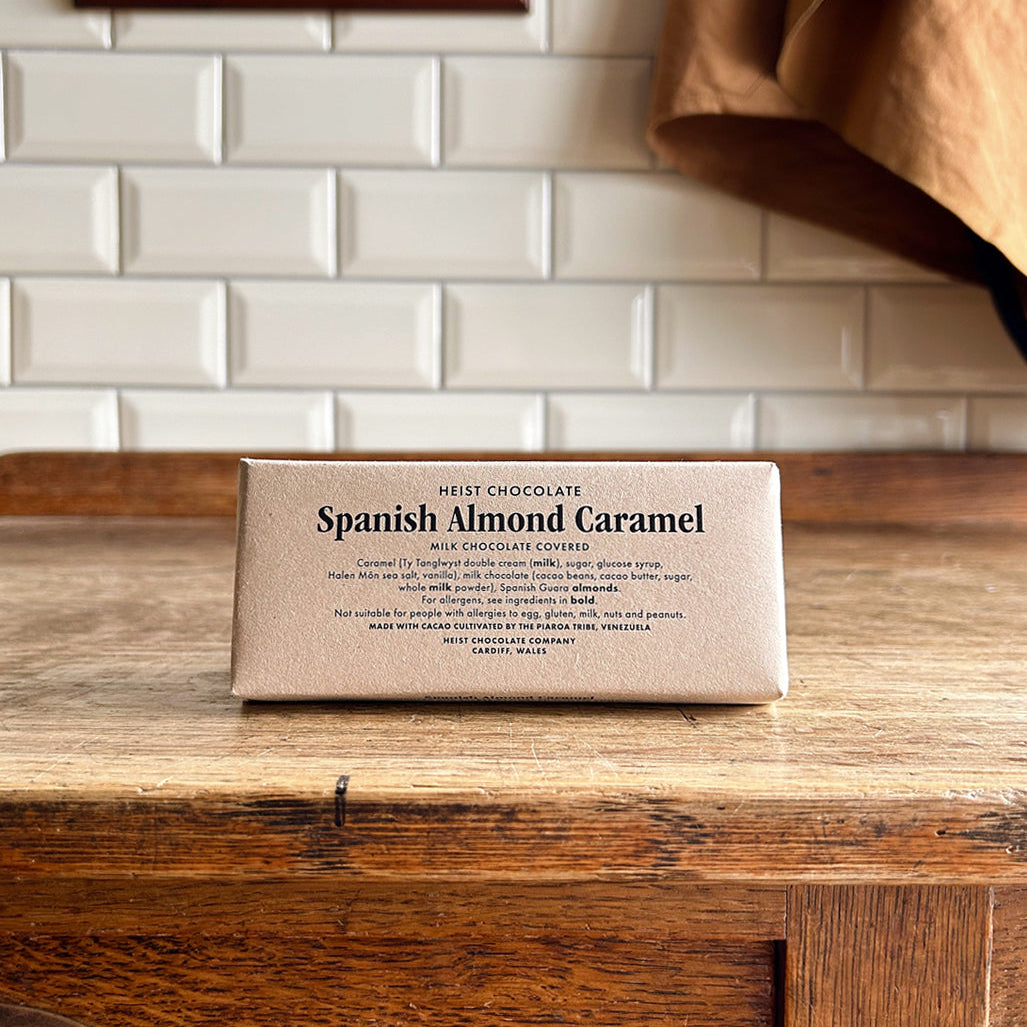 Bar of Spanish Almond Caramel chocolate on a wooden surface with a tiled wall in the background